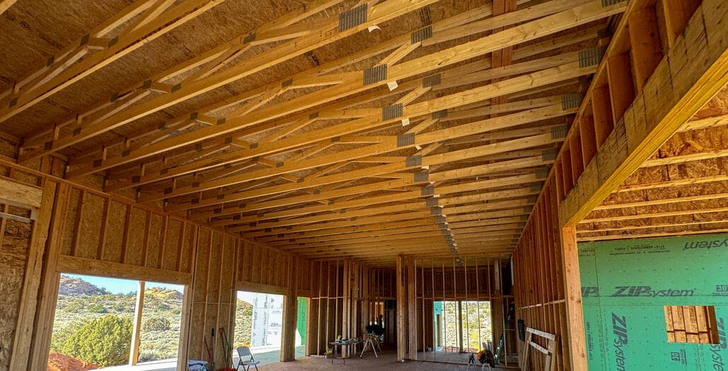 Interior of a framed great room, scissor trusses and open studs with the desert visible through the window openings