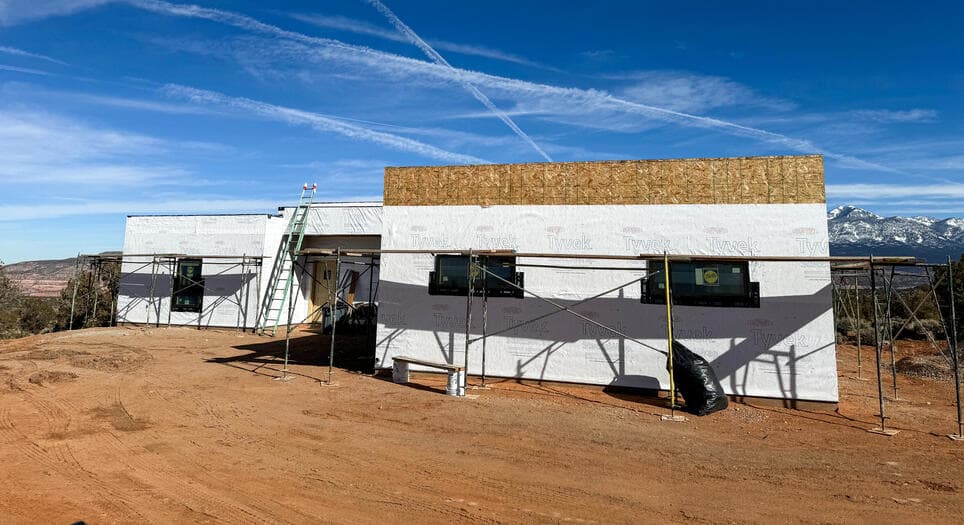 House wrap and scaffolding on a Moab home with the snow-capped La Sal Mountains behind it
